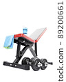 Dumbbells beneath a workout bench with towel and water bottle 89200661