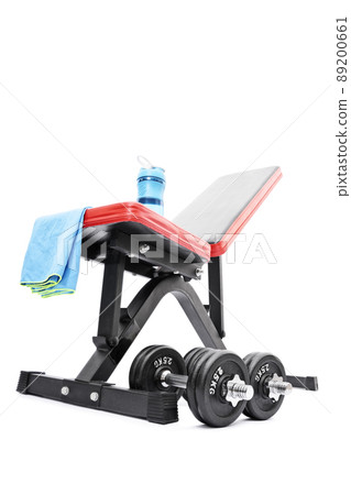 Dumbbells beneath a workout bench with towel and water bottle Dumbbells beneath a workout bench with towel and water bottle 89200661