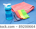 Resistance rubber bands, towel and water bottle on blue mat 89200664
