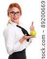 Young businesswoman holding apple and raising thumb up 89200669