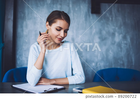 Attractive woman with smartphone and paper in workspace Attractive woman with smartphone and paper in workspace 89200722