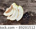 Sweet ripe melon cut on a wooden table with spilling seeds. 89201512