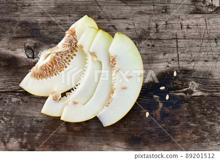Sweet ripe melon cut on a wooden table with spilling seeds. Sweet ripe melon cut on a wooden table with spilling seeds. 89201512