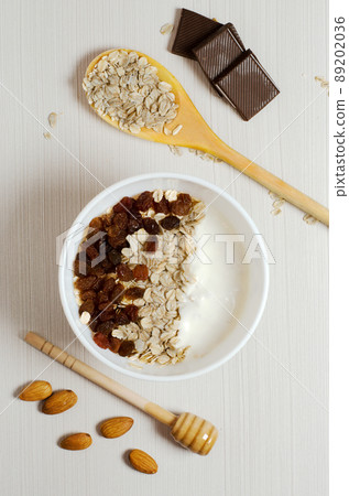 Oatmeal with raisins and yogurt. Oatmeal in the wooden spoon. Almond, chocolate. Flat top view 89202036