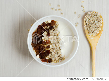 Oatmeal with raisins and yogurt. Oatmeal in the wooden spoon. Flat top view Oatmeal with raisins and yogurt. Oatmeal in the wooden spoon. Flat top view 89202037