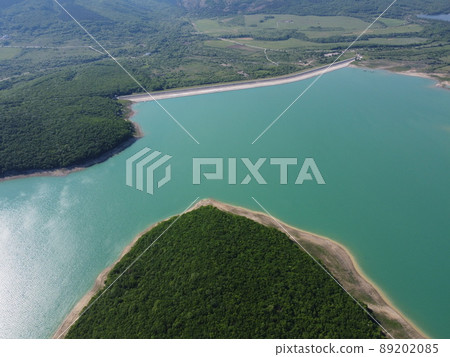 Aerial view on water reservoir at mountain valley covered with green spring forest. Beautiful view from above on smooth blue surface of mountain lake among highlands. drone point of view 89202085