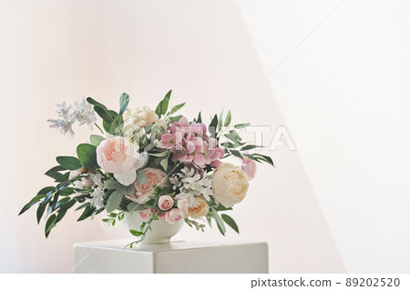 A composition of different flowers in a white vase on a square podium. The concept of a flower shop. A beautiful freshly cut bouquet. Flower delivery. High quality photo A composition of different flowers in a white vase on a square podium. The concept of a flower shop. A beautiful freshly cut bouquet. Flower delivery. High quality photo 89202520