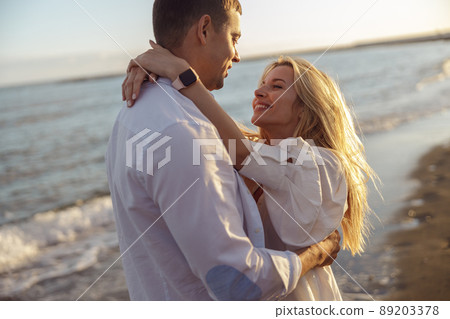 Portrait of happy couple hugging while standing on beach 89203378