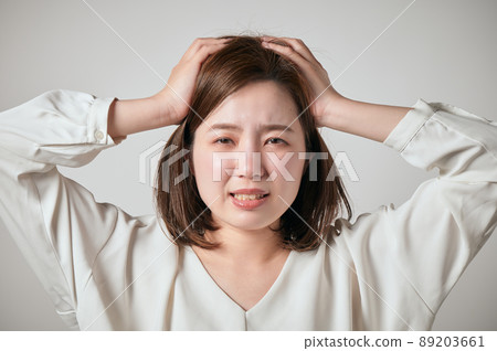A young woman holding her head with both hands A young woman holding her head with both hands 89203661