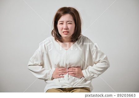 A young woman who has a stomachache and can hold her hands 89203663