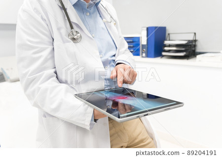 Unrecognizable Doctor is checking x-ray image at computer tablet, close up. Doctor at work in a 89204191