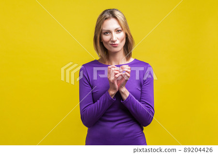 Portrait of cunning beautiful businesswoman in purple dress clasping hands and planning evil tricky prank or scheming, cheating with sly smile. indoor studio shot isolated on yellow background Portrait of cunning beautiful businesswoman in purple dress clasping hands and planning evil tricky prank or scheming, cheating with sly smile. indoor studio shot isolated on yellow background 89204426
