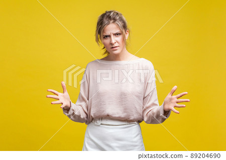Portrait of annoyed disappointed woman with fair hair in casual blouse standing with raised arms, frustrated and angry while arguing. indoor studio shot isolated on yellow background Portrait of annoyed disappointed woman with fair hair in casual blouse standing with raised arms, frustrated and angry while arguing. indoor studio shot isolated on yellow background 89204690