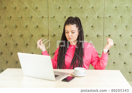 Time to relax. Successful young girl freelancer with black dreadlocks hairstyle in pink blouse are having a rest, holding hands like have meditative to have emotional pleasure. Indoor, sitting in cafe Time to relax. Successful young girl freelancer with black dreadlocks hairstyle in pink blouse are having a rest, holding hands like have meditative to have emotional pleasure. Indoor, sitting in cafe 89205143