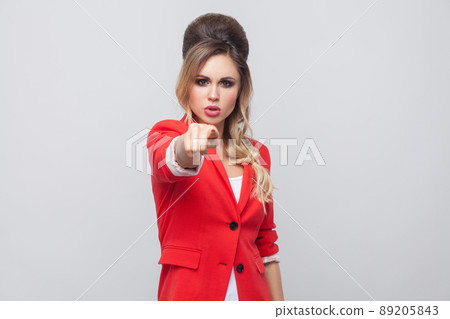 Hey you. Portrait of serious beautiful business lady with hairstyle and makeup in red fancy blazer, standing, looking at pointing at camera. indoor studio shot, isolated on grey background. Hey you. Portrait of serious beautiful business lady with hairstyle and makeup in red fancy blazer, standing, looking at pointing at camera. indoor studio shot, isolated on grey background. 89205843