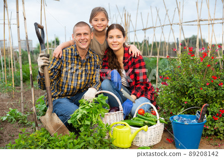 Couple of gardeners with child posing with harvest of vegetables Couple of gardeners with child posing with harvest of vegetables 89208142