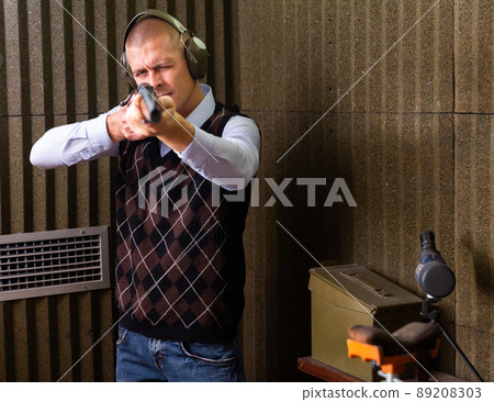 Concentrated man practicing shotgun shooting at firing range 89208303