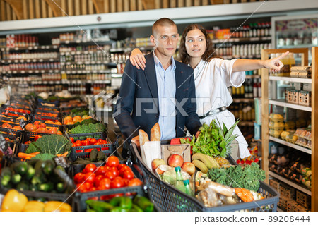 Wife points out something to her husband at grocery store Wife points out something to her husband at grocery store 89208444