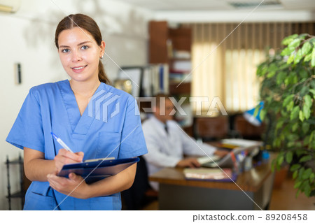 Positive confident young female doctor in a resident's office, writes important notes 89208458