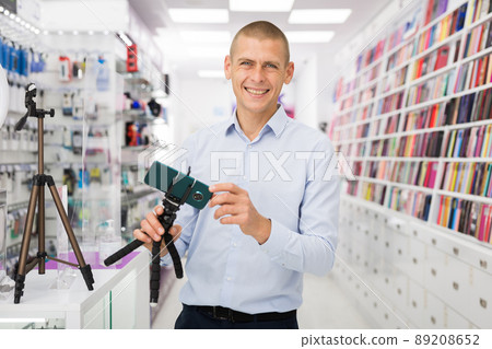 Male customer buying tripod at the multimedia store 89208652