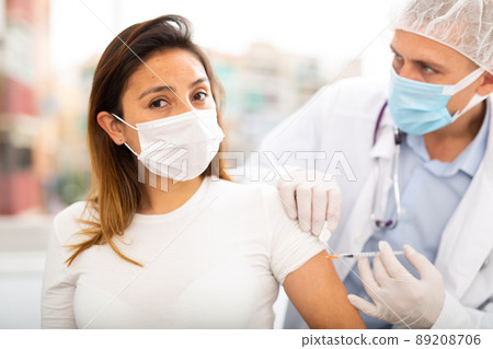 doctor in protective face mask vaccinates woman doctor in protective face mask vaccinates woman 89208706