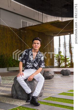 Portrait of cool young man outdoors during summer sitting full length shot 89211751
