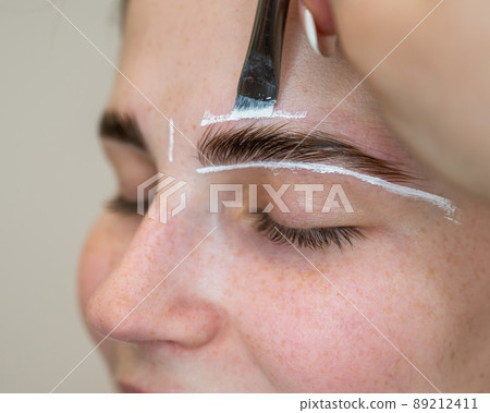 The master draws the shape of the eyebrows with white paint before coloring. The master draws the shape of the eyebrows with white paint before coloring. 89212411