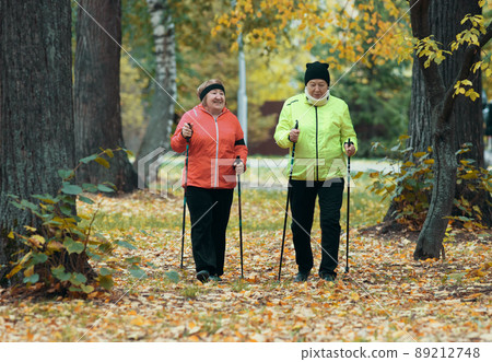 Mature women walking in an autumn park during a scandinavian walk. 89212748