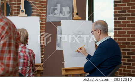 Elder man and woman drawing on canvas in art class, attending educational lesson at community centre. Senior people learning to draw sketch masterpiece with teacher, workshop practice. Elder man and woman drawing on canvas in art class, attending educational lesson at community centre. Senior people learning to draw sketch masterpiece with teacher, workshop practice. 89212810