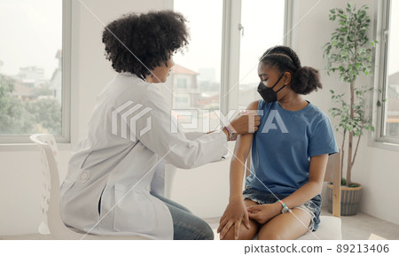 African american doctor is applying plaster to a child's shoulder after being vaccinated. Opening sleeves to vaccinate against flu or epidemic in health care and vaccinated concept. 89213406