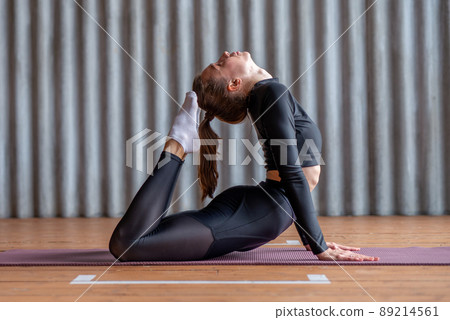 Woman working out arching her back and reaching her toes for her head Woman working out arching her back and reaching her toes for her head 89214561