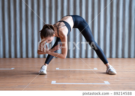 Woman exercising standing forward bend stretches of legs and lower back. 89214588