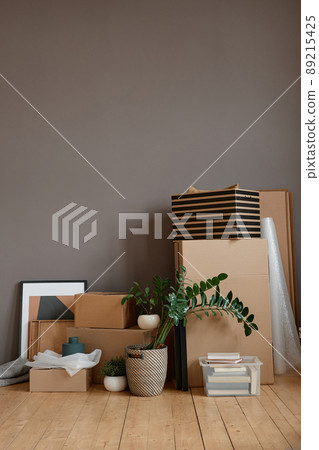 Vertical no people shot of unpacked cardboard boxes and objects placed in loft room against gray wall 89215425