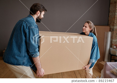 Horizontal shot of young man and woman moving to new apartment carrying big heavy box together Horizontal shot of young man and woman moving to new apartment carrying big heavy box together 89215467