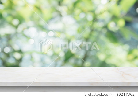 Marble table top with blur green leaf bokeh nature background Marble table top with blur green leaf bokeh nature background 89217362