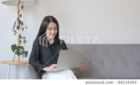 Attractive woman using computer laptop on sofa while spending leisure time at home. 89218393