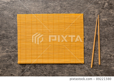 Two chopsticks and bamboo mat on cement background. Top view, copy space Two chopsticks and bamboo mat on cement background. Top view, copy space 89221380