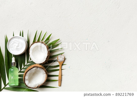 Coconut with jars of coconut oil and cosmetic cream on colored background. Top view. Free space for your text. Natural spa coconut cosmetics and organic treatment concept Coconut Spa composition 89221769