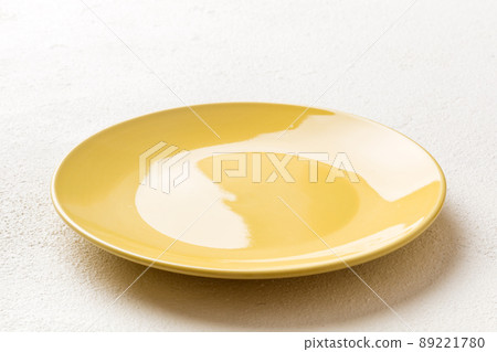 Perspective view of empty yellow plate on cement background. Empty space for your design Perspective view of empty yellow plate on cement background. Empty space for your design 89221780