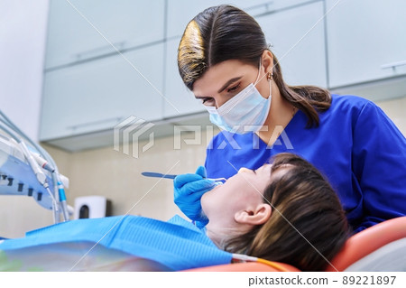 Doctor dentist treats teeth to a young teenage female patient 89221897