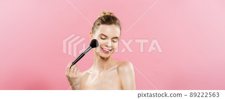 Beauty Concept - Closeup Beautiful caucasian woman applying makeup with Cosmetic Powder Brush. Perfect Skin. Isolated on pink background and copy space. 89222563