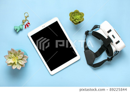 white tablet with black screen display, vr glasses for virtual reality games on blue background Top view Flat lay Mock up Technology concept Copy space. 89225844