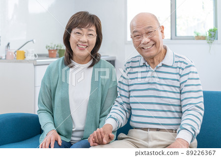 在家客廳的沙發上並排坐著的老夫婦 89226367