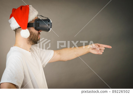 Man in virtual reality goggles and santa hat 89226502