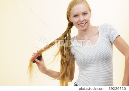 Blonde girl brushing her long hair Blonde girl brushing her long hair 89226510