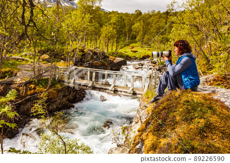 Tourist with camera at river, Norway 89226590