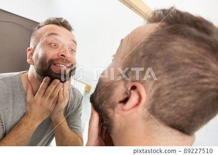 Man looking at beard in mirror Man looking at beard in mirror 89227510