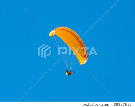 Paraglider flying in blue sky. 89227652