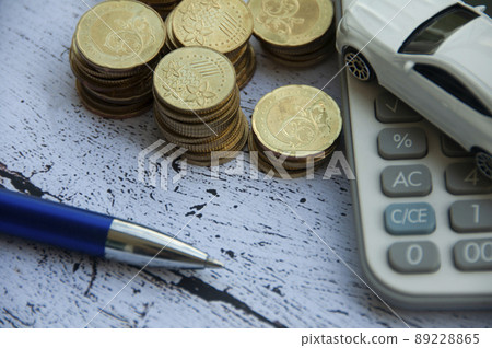 Gold coins, calculator, white car toy and pen on wooden background. Selective focus on coins. Finance concept 89228865