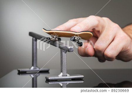 A man rolls a fingerboard on a metal railing, close-up 89230669